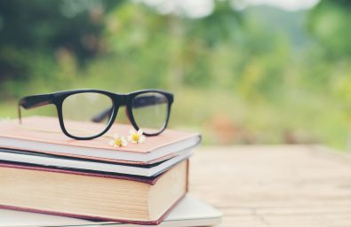 Book and eye glasses for read and write over blurred nature outdoor background.