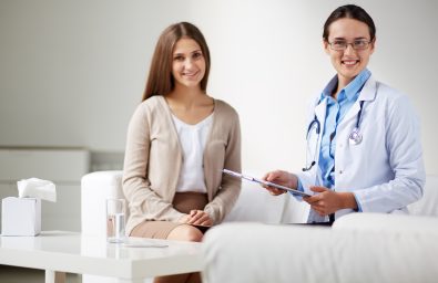 Female psychiatrist looking at camera with her patient near by